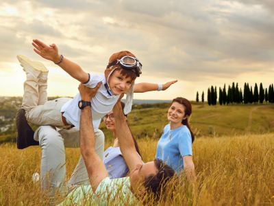 Famiglia felice gioca nei campi, il bambino vola sorridendo.