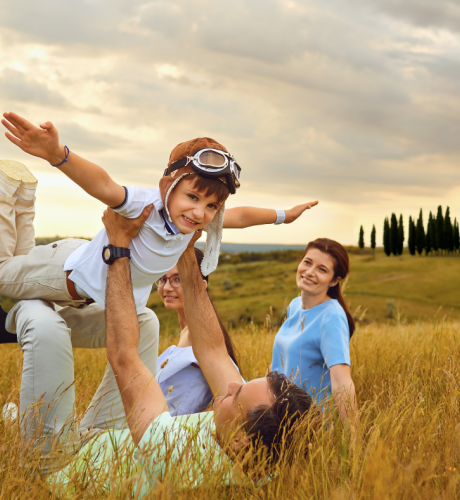 Famiglia felice gioca nei campi, il bambino vola sorridendo.
